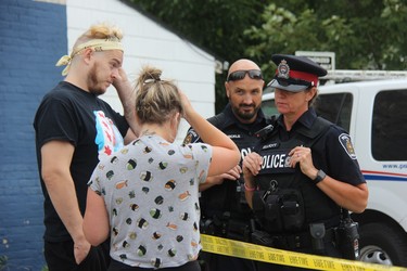 London police talk to Laura Earle and her boyfriend Chris Patterson, whose house was severely damaged following a Wednesday night explosion on Woodman Avenue after a car hit a gas line in the area. (JONATHAN JUHA, The London Free Press)