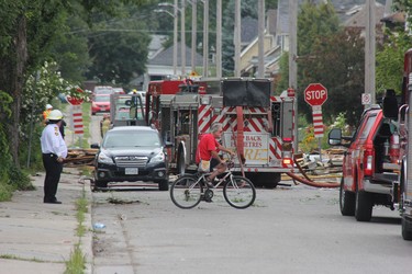 Londoner Rauk Zenta rides his bike near the site of a Wednesday night explosion on Woodman Avenue. The man said he heard about the explosion and wanted to check on a friend who lives on the street. (JONATHAN JUHA, The London Free Press)