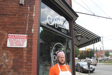 Kaleb Elie with the Artisan Bakery on Dundas Street near Rectory. The Old East Village business is collecting the artwork of a young girl whose home blew up this week. Her drawings, still floating around the neighbourhood - some more than a kilometre away - are believed to have been blown out of the house when a car crashed into it, but before it was leveled by an explosion and fire. (Sebastian Bron/The London Free Press)