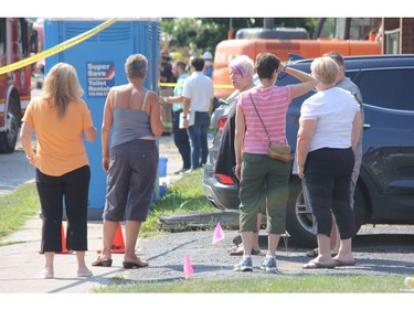 Woodman Avenue residents survey on Friday the site of a explosion that forced them out of their homes Wednesday night after a vehicle slammed into a home at 450 Woodman and severed a gas line. (JONATHAN JUHA, The London Free Press)