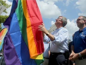 Ottawa mayor Jim Watson (centre) helps to raise the colourful flag at City Hall Monday to kick off Pride Festival in Ottawa this week.
