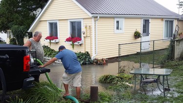 Rick Barnier (left) and a friend who declined to give his name pump flood water from the yard of an Erie Shores Drive home in Chatham-Kent. Earlier flooding causes by strong winds and high water levels had prompted Chatham-Kent Mayor Darrin Canniff to declare a state of emergency Tuesday and ask area residents to voluntarily evacuate.  TREVOR TERFLOTH/CHATHAM DAILY NEWS/POSTMEDIA NETWORK