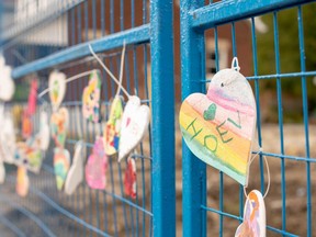 Decorated hearts hang from the blue fence that blocks off homes on Woodman Avenue that were damaged or destroyed in an explosion two weeks ago. (Max Martin, The London Free Press)