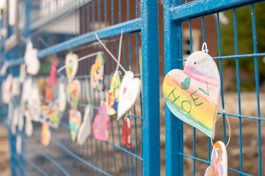 Decorated hearts hang from the blue fence that blocks off homes on Woodman Avenue that were damaged or destroyed in an explosion two weeks ago. (Max Martin, The London Free Press)