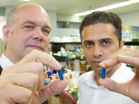 Saman Maleki, right, and Lawson researcher Jeremy Burton hold up capsules used for research into fecal transplants for patients with melanoma in London in 2019. Photograph taken on Aug. 16, 2019. (Mike Hensen/The London Free Press)