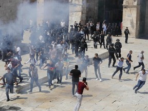 Palestinians run for cover from sound grenades at the al-Aqsa Mosque compound in the Old City of Jerusalem on August 11, 2019. (Photo by Ahmad GHARABLI / AFP)