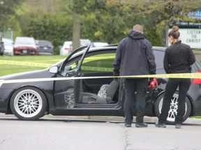 London police officers inspect a vehicle at the scene of a shooting at the corner of Trafalgar Street and Admiral Drive. Photo taken May 11, 2019. (JONATHAN JUHA, The London Free Press)