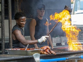 Chimba Musafiri, of Hamilton, Ont., uses a grease soaked brush to summon flames from his grill at Rib Fest in Victoria Park in London, Thursday Aug. 1, 2019. Musafiri works at the Oak and Barrel rib joint. Derek Ruttan/The London Free Press