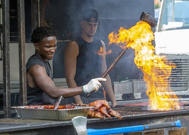 Chimba Musafiri, of Hamilton, Ont., uses a grease soaked brush to summon flames from his grill at Rib Fest in Victoria Park in London, Thursday Aug. 1, 2019. Musafiri works at the Oak and Barrel rib joint. Derek Ruttan/The London Free Press