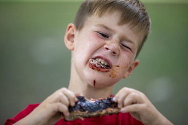 Cohen Dyke rips into lunch at The London Rib Fest and Craft Beer Festival in Victoria Park in London, Ont. on Monday August 5, 2019. "I love ribs better than anything," said the five-year-old Aylmer native. "They're amazing, amazing, amazing!" He was visiting with his dad Johnny, mom Netty, brother Tucker and sister Brianna.Derek Ruttan/The London Free Press/Postmedia Network