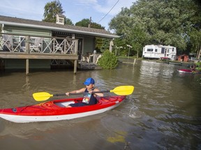 The Riker Carlsen, 9, and his brother Keller, 11, of Chatham, paddle their kayaks through the front yards of neighbours of their grandfather Randy Morton in Erieau on Tuesday Aug. 27, 2019. The boys were staying with their grandfather, whose trailer is on higher ground and was untouched by the higher water levels. (Derek Ruttan/The London Free Press)
