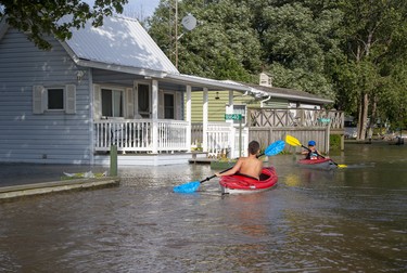 The Keller Carlsen, 11, left, and his brother Riker, 9, of Chatham paddle their kayaks through the front yards of neighbours of their grandfather, Randy Morton, in Erieau on Tuesday Aug. 27, 2019. The boys were staying with their grandfather, whose trailer is on higher ground and was untouched by the high water. Derek Ruttan/The London Free Press