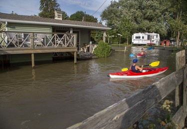 The Keller Carlsen, 11, rear, and his brother Riker, 9, of Chatham paddle their kayaks through the front yards of neighbours of their grandfather, Randy Morton, in Erieau on Tuesday Aug. 27, 2019. The boys were staying with their grandfather, whose trailer is on higher ground and was untouched by the high water. Derek Ruttan/The London Free Press