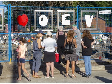 People look at painted hearts decorating a fence that surrounds homes that were damaged and destroyed by a gas explosion two weeks ago in London. A street party was held in support of the neighbourhood on Wednesday. (Derek Ruttan/The London Free Press)