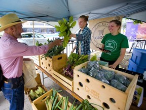Lewis Seale gets some miniature turnips from Rosa Kniivila and Madison Smith at the Urban Roots market that has set up just east of Adelaide on Dundas Street in front of the Old East Village grocer in London, Ont.  (Mike Hensen/The London Free Press)