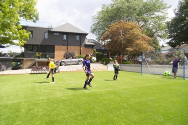 Glen Martins watches daughters Bella, 10, Tienna, 12 and Sofia, 8, practise their ball-handling skills in the sideyard of their Byron home which boasts an artificial turf soccer pitch. (Mike Hensen/The London Free Press)