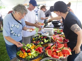 Marj McLeish and Chris Fox wait in line as volunteer Kate Ahrens hands out some watermelon during a picnic in support of Old East London village held at Boyle Memorial Community Centre on Sunday August 18, 2019. About 400 people attended the free event. Ahrens' who lives in the village said, "I just showed up and said, 'how can I help.'" (Mike Hensen/The London Free Press)