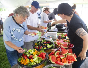 Marj McLeish and Chris Fox wait in line as volunteer Kate Ahrens hands out some watermelon during a picnic in support of Old East London village held at Boyle Memorial Community Centre on Sunday August 18, 2019. About 400 people attended the free event. Ahrens' who lives in the village said, "I just showed up and said, 'how can I help.'" (Mike Hensen/The London Free Press)