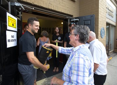 AJ Braatz of the London Fire Department accepts a donation from Carol Carroll(cct) at the Old East Village benefit concert being held at the Aeolian Hall on Dundas Street.  Mike Hensen/The London Free Press/Postmedia Network