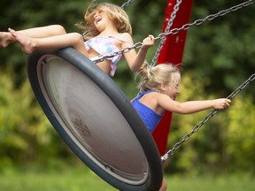 Chloe Rea, 7, and Layla Peters, 6, have a great time sharing a big swing at the playground in Springbank Park on Friday August 23, 2019.  Mike Hensen/The London Free Press