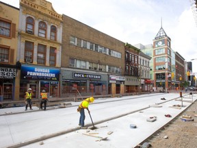 Tyler Hubbert of Ailsa Craig removes forms from the freshly laid concrete on Dundas Street just east of Richmond on Monday.  The big slab was poured last week and in three weeks approximately they will be starting to put down the interlocking stone surface Amico officials said. (Mike Hensen/The London Free Press)