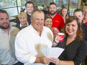 Chris Sparling, who owns the Tim Horton's at Egerton and Dundas hands over $33,000 in cheques to Kate Graham, a volunteer at the Old East Village Community Association. Sparling is surrounded by other Tim Horton's franchise owners representing all the stores in London that raised funds that were matched by Tim Horton's head office to help those affected by the gas explosion in London, Ont.  (Mike Hensen/The London Free Press)