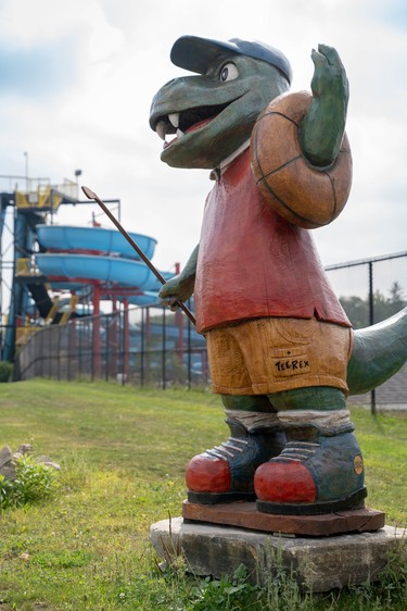 A "tee-rex" mascot at East Park is the newest edition to the Hamilton Road tree trunk tour. It's holding an inner tube and a golf club, a reference to two of the park's hallmark activities.  (MAX MARTIN, The London Free Press)