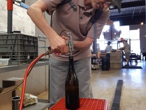 Columnist Wayne Newton tries his hand at bottling Dark Side Chocolate Stout by hand during Brewed Exploration at Upper Thames Brewing in Woodstock. (Tiffany Martin/Travelling Pint photo)