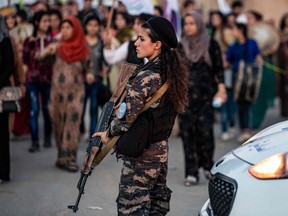 A member of the Kurdish Internal Security Police Force of Asayish stands guard as Syrian Kurdish demonstrate against Turkish threats to invade the Kurdish region, in the northeastern city of Qamishli on August 27, 2019. - The Kurdish authorities in northeast Syria said Tuesday their forces had started to withdraw from outposts along the Turkish border after a US-Turkish deal for a buffer zone there. (Photo by DELIL SOULEIMAN/ AFP/Getty Images