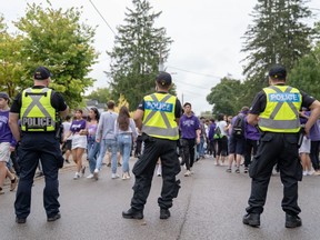 Police officers stand by as students and young people crowd onto Broughdale Avenue during the annual Fake Homecoming (FoCo) celebrations on Saturday, Sept. 28, 2019. (MAX MARTIN, The London Free Press)