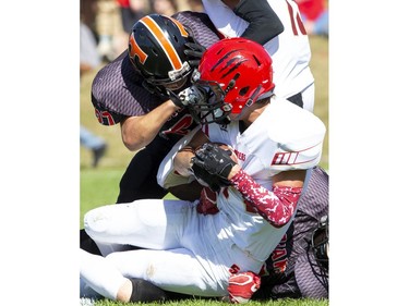 Tyler Lauzon of the Clarke Road Trojans grabs hold of the face mask to tackle Nathan Hicks of the Saunders Sabres during the United Way game in London on Thursday Sept. 19, 2019. Students were allowed to miss classes and attend the game by purchasing a ticket to the United Way fund raiser. (Derek Ruttan/The London Free Press)