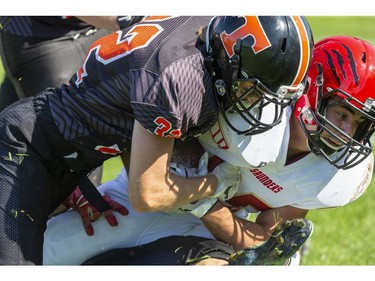 Taylor Sweeney of the Clarke Road Trojans tackles Nate Laforge of the Saunders Sabres during the United Way game in London on Thursday Sept. 19, 2019. Students were allowed to miss classes and attend the game by purchasing a ticket to the United Way fund raiser. (Derek Ruttan/The London Free Press)