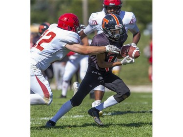 Clarke Road Trojan Devonte Wickens catches a pass while pursued by Ty Fletcher of the Saunders Sabres during their United Way football game at Saunders Secondary School in London, Ont. on Thursday September 19, 2019. The home team won the game 28-0. (Derek Ruttan/The London Free Press)