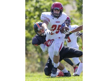 Clarke Road Trojan Corey Griffin tackles Nate Laforge of the  Saunders Sabres during the United Way game in London on Thursday Sept. 19, 2019. Students were allowed to miss classes and attend the game by purchasing a ticket to the United Way fund raiser. (Derek Ruttan/The London Free Press)