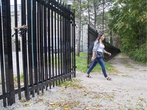 Public health master's degree student Kelsie McGregor walks through a gated fence that separates Western University from Broughdale Avenue in London on Wednesday as part of an effort to tamp down an annual overcrowded party on the street. McGregor is avoiding this weekend's festivities by heading home to Manitoulin Island. (Derek Ruttan/The London Free Press)