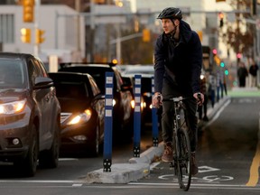 A cyclist keeps a wary eye on traffic in the left-hand turning lane before proceeding. (Postmedia Network file photo)