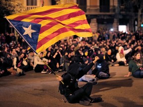 A protester waves a Catalan pro-independence "Estelada" flag during a protest outside the Spanish Government regional office in Barcelona on October 21, 2019. - The nightly violence in Catalonia has dominated the news in Spain and made headlines around the world, but so far, Madrid has shown little appetite for direct intervention, despite repeated calls for regional president Quim Torra to condemn the unrest. (Photo by Pau Barrena / AFP)