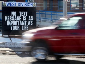 Motorists make their way past an anti distracted driving sign outside the EPS West Division Police Station, 16505 - 100 Ave., in Edmonton, Alta. File photo.