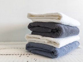 A stack of white and grey bath towels on white wooden table. Spa and wellness, cotton terry textile.