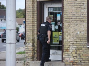 A London police officer is seen Wednesday afternoon entering a variety store in the area of Wharncliffe Road and Byron Avenue as police searched for a suspect in connection with a robbery investigation. (JONATHAN JUHA, The London Free Press)
