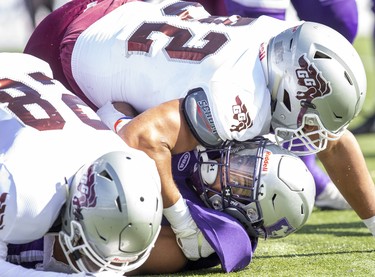 Western Mustang ball carrier feels the full weight of Ottawa Gee Gee tacklers Reshaan Davis (on top) and Alex Douglas during their game in London, Ont. on Saturday October 19, 2019. Derek Ruttan/The London Free Press/Postmedia Network