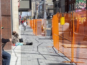 A man rests on the ground on the north side Dundas Street east of Richmond Street in downtown London on Wednesday. The city's main street is under reconstruction for below-ground infrastructure and a flex street that can be converted to a car-free space for special events. (Derek Ruttan/The London Free Press)