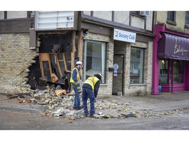 Restoration workers collect bricks littering the sidewalk and street after a car tore open a wall of the Society Cafe at the corner Blackfriars Street and Wilson Avenue before crashing into a house at 45 Blackfriars St. in London, Ont. on Sunday Oct. 27, 2019. (Derek Ruttan/The London Free Press)