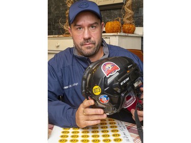 Adam Stafford of Komoka holds a hockey helmet with the sticker 873, in honour of Tyler Coleiro, 18 who died in an automobile crash near Komoka last week. The helmet sticker fundraiser has proceeds going to the Coleiro family. Photograph taken on Thursday October 31, 2019.  (Mike Hensen/The London Free Press)