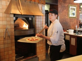 Bertoldi's Trattoria cook Sarah Rice puts a pizza in the oven during the lunch rush Monday. The downtown restaurant is closing its doors Saturday after 18 years on Richmond Row. (Jennifer Bieman/The London Free Press)