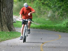 A cyclist checks the time as he heads down a bicycle path that follows the Thames River near the forks. (File photo)