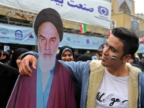 An Iranian man poses with a life-size cutout portrait of Islamic Revolution founder Ayatollah Ruhollah Khomeini during a ceremony celebrating the 40th anniversary of Islamic Revolution in the capital Tehran on February 11, 2019. (Photo by ATTA KENARE/AFP/Getty Images)