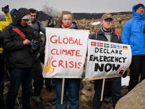 People hold up signs as a monument was unveiled at the site of Okjokull, Iceland's first glacier lost to climate change in the west of Iceland on August 18, 2019. (Photo by Jeremie RICHARD / AFP)