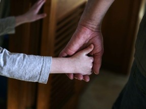 A man and child hold hands in Springfield, Mass. in a Saturday, Dec. 12, 2015 photo. Family caregivers in Ontario now have a help line if they're needing respite, a support group or information on issues including tax credits.