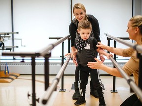 Handout/Chatham Daily News Bentley Hann and his mom Amanda work with physiotherapist Sarah Reed on the new set of parallel bars at the Children's Treatment Centre of Chatham-Kent recently donated by the Plasman Group in Tilbury.
